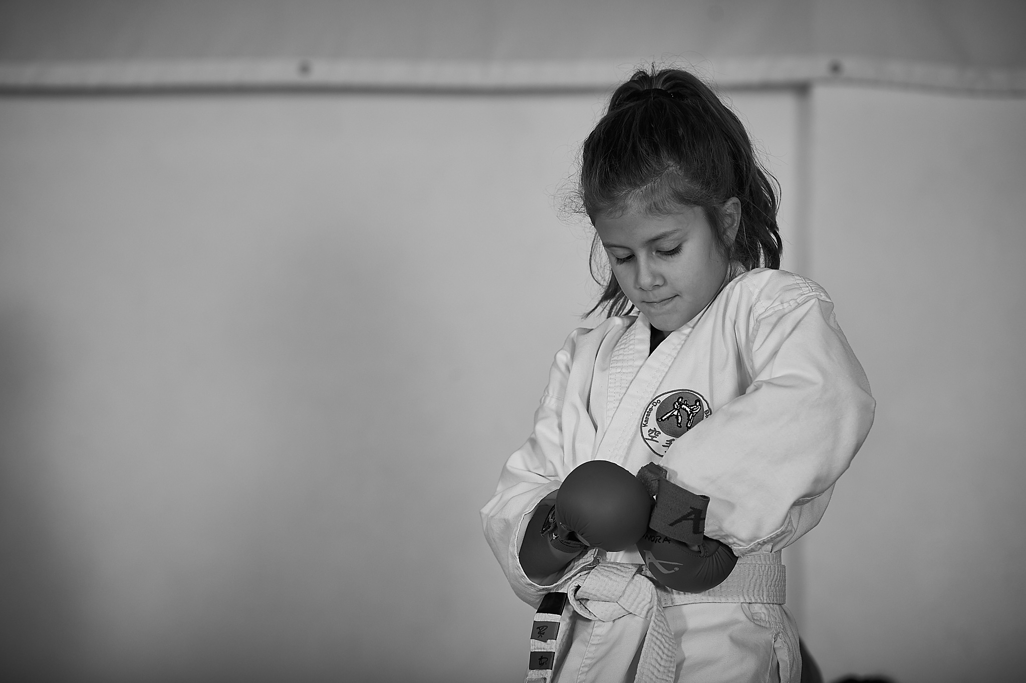 ZEN SHIN Karate U8 Bonsai Maedchen am anziehen der Karatehandschuhe